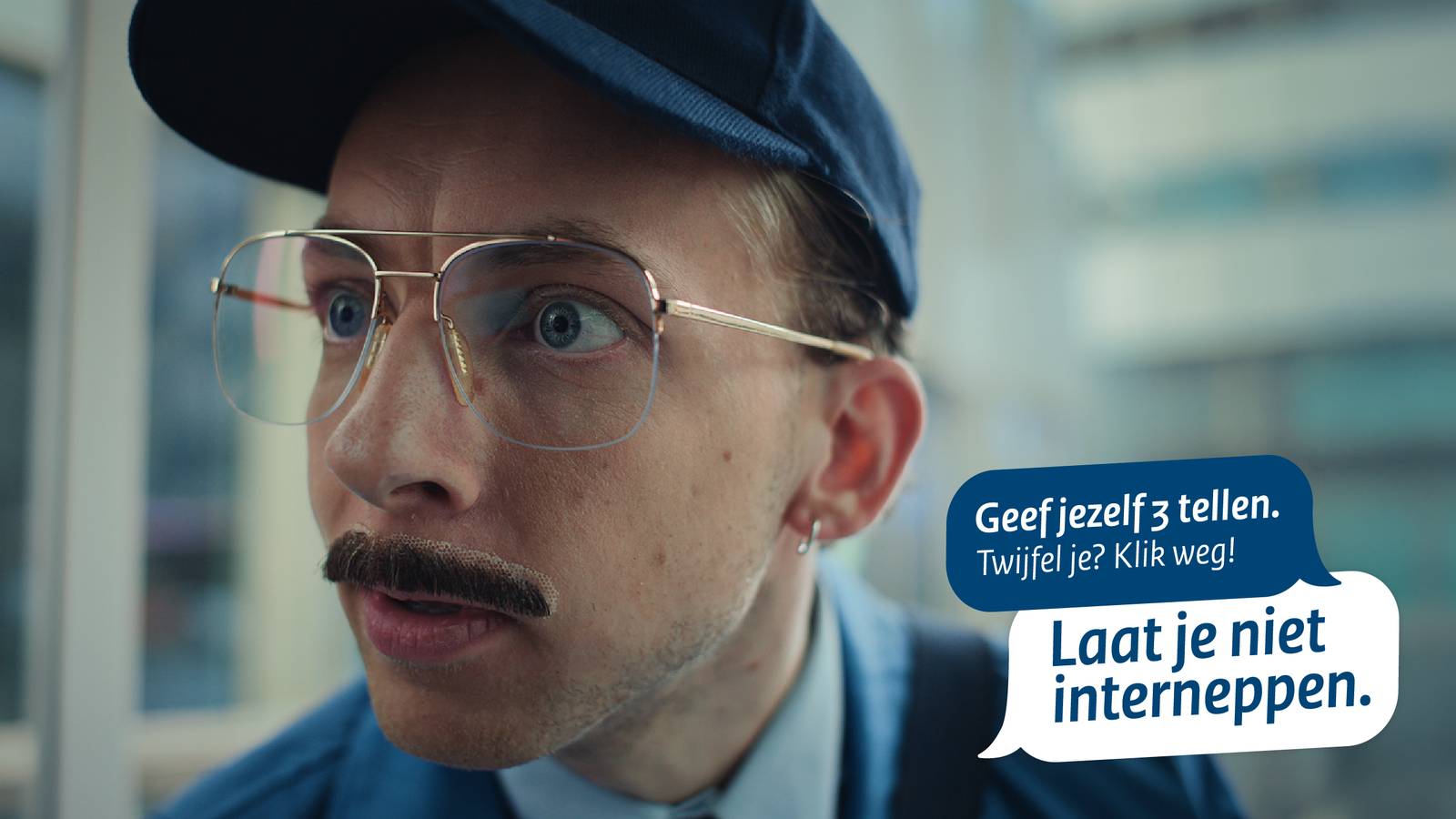 Afbeelding voor de campagne van Laat je niet interneppen. Een man met blauwe pet, grote bril en een plaksnor met duidelijke lijmresten erom heen. In blauw kader staat de tekst Geef jezelf 3 tellen. Twijfel je? Klik weg!. In wit kader staat Laat je niet interneppen.