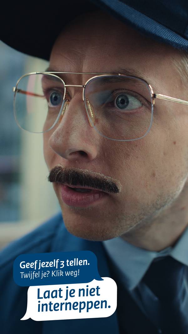 Afbeelding voor de campagne van Laat je niet interneppen. Een man met blauwe pet, grote bril en een plaksnor met duidelijke lijmresten eromheen. In blauw kader staat de tekst Geef jezelf 3 tellen. Twijfel je? Klik weg!. In wit kader staat Laat je niet interneppen.