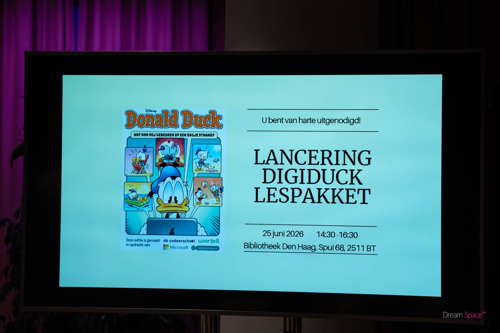 Afbeelding van een beamerscherm met daarop een afbeelding van een Donald Duck en de tekst Lancering DigiDuck lespakket
